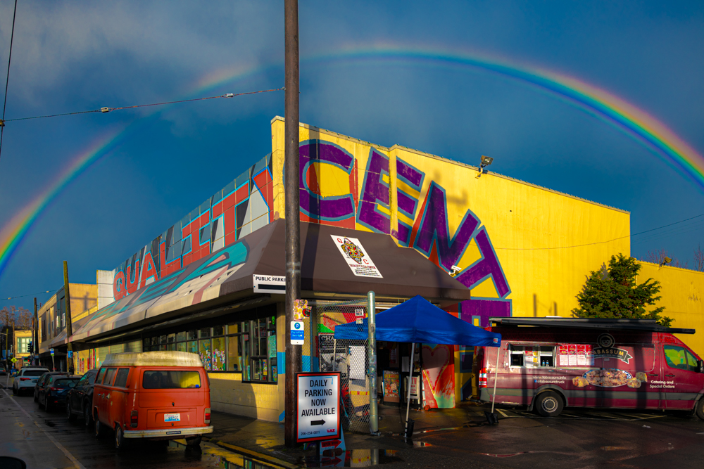The yellow Quality Flea Center building on 15th Ave E under a double rainbow